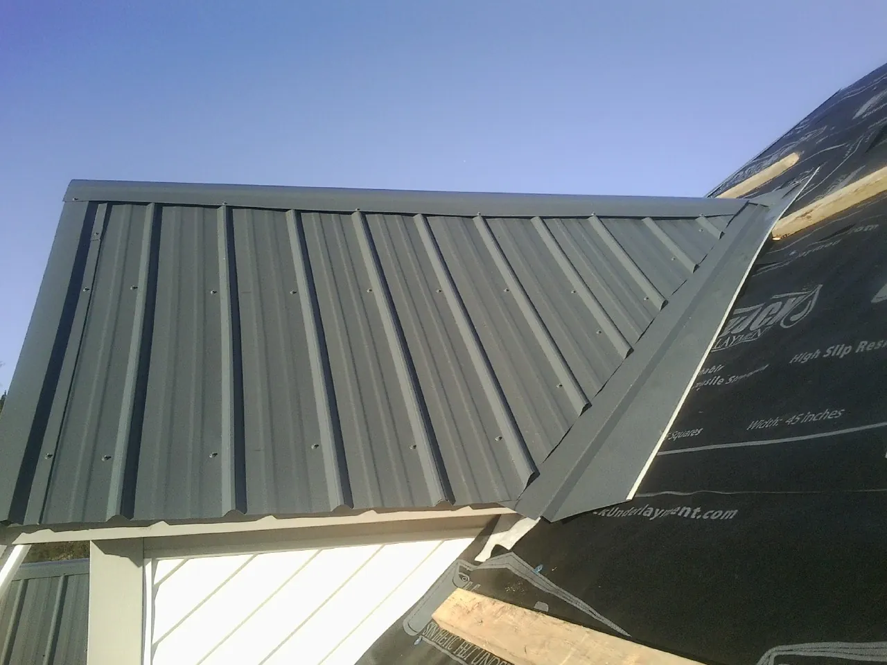 Gray metal roof panels going on over a garage gable in Atkinson