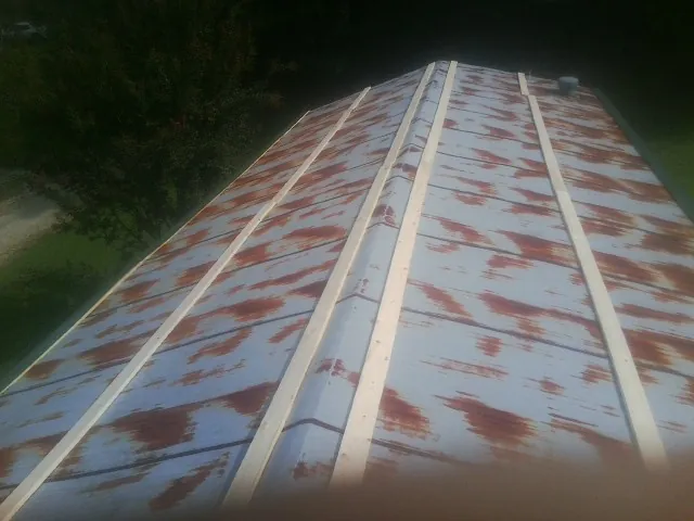 Rusted metal roof panels with new wood purlins before replacement — Storm Damage Roof Repair in Atkinson by Roofing Brothers